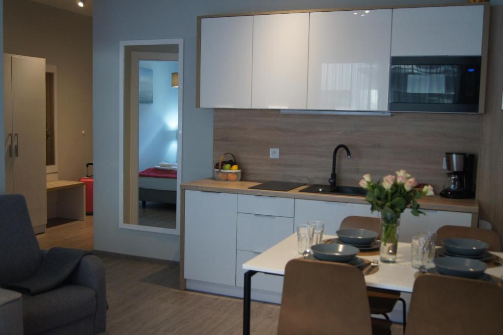 a kitchen with white cabinets and a table with flowers on it at Apartament Elvira, Grunwaldzka 12C in Pobierowo