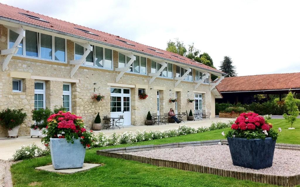 un edificio con due grandi vasi di fiori nel cortile di La Grange Champenoise ad Auménancourt-le-Grand