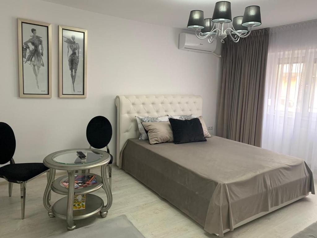 - une chambre avec un lit, une table et un lustre dans l'établissement Leon Apartment, à Brăila