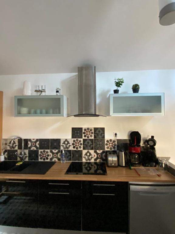 a kitchen with black and white tiles on the wall at Le Mahonia in Yport
