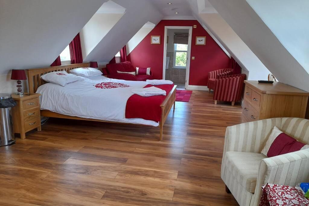 ein Schlafzimmer mit roten Wänden und einem Bett und einem Sofa in der Unterkunft THE STUDIO ROUGHTON in Roughton