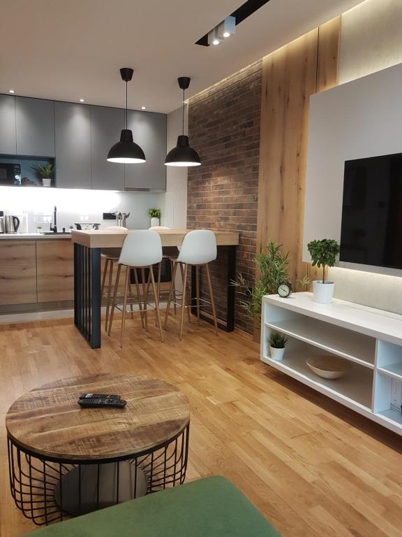 a kitchen and living room with a table and a tv at Tesla 3 Apartment in Novi Sad