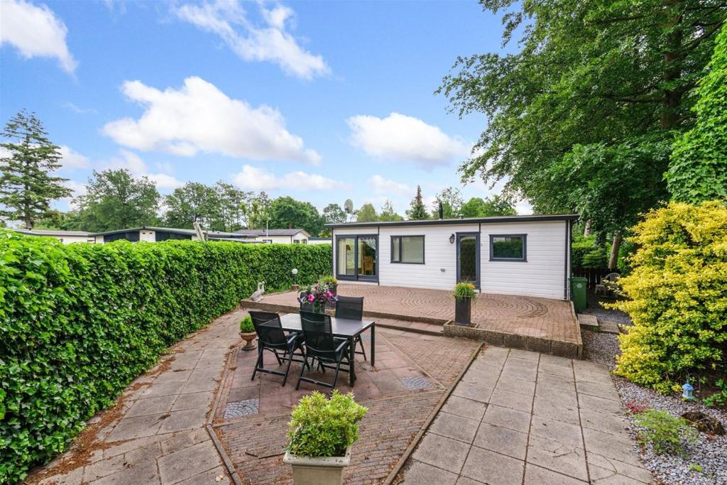 a tiny house in a garden with a table and chairs at Charmant chalet te Voorthuizen in Voorthuizen