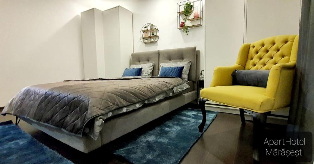 a bedroom with a bed and a yellow chair at ApartHotel Marasesti in Suceava