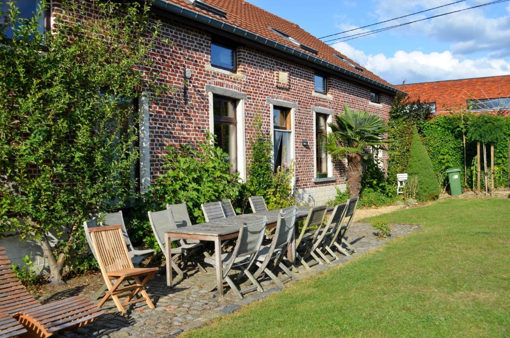 une table et des chaises en bois devant une maison en briques dans l'établissement Hageland Vakantieverblijf, à Holsbeek