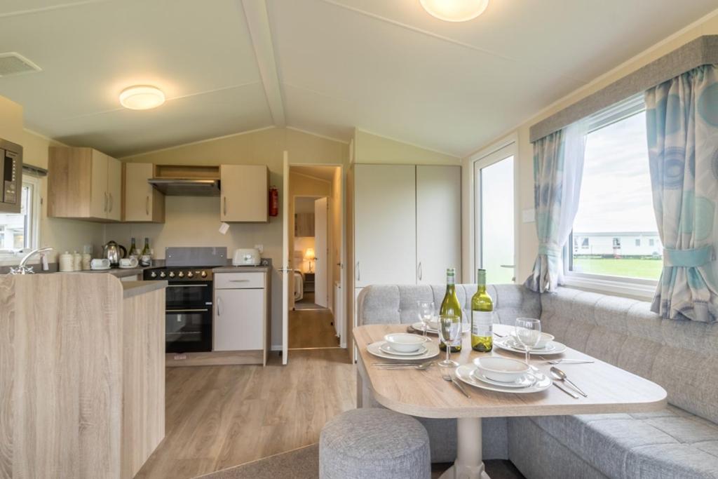 a kitchen and living room with a table with plates and wine bottles at The Shack - plot NB139 in Porth