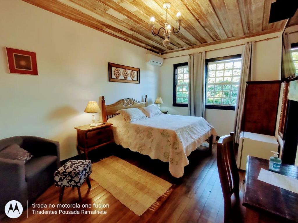 ein Schlafzimmer mit einem Bett, einem Stuhl und einem Sofa in der Unterkunft Tiradentes Pousada Ramalhete in Tiradentes