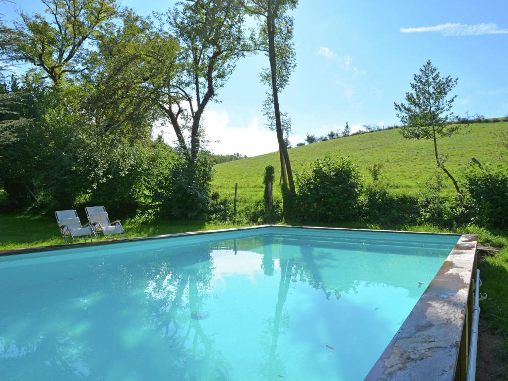a swimming pool with a hill in the background at Sunny water mill with heated swimming pool in Brandonnet
