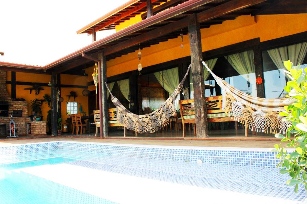 a house with a swimming pool with hammocks in it at Reduto do Alto in Búzios