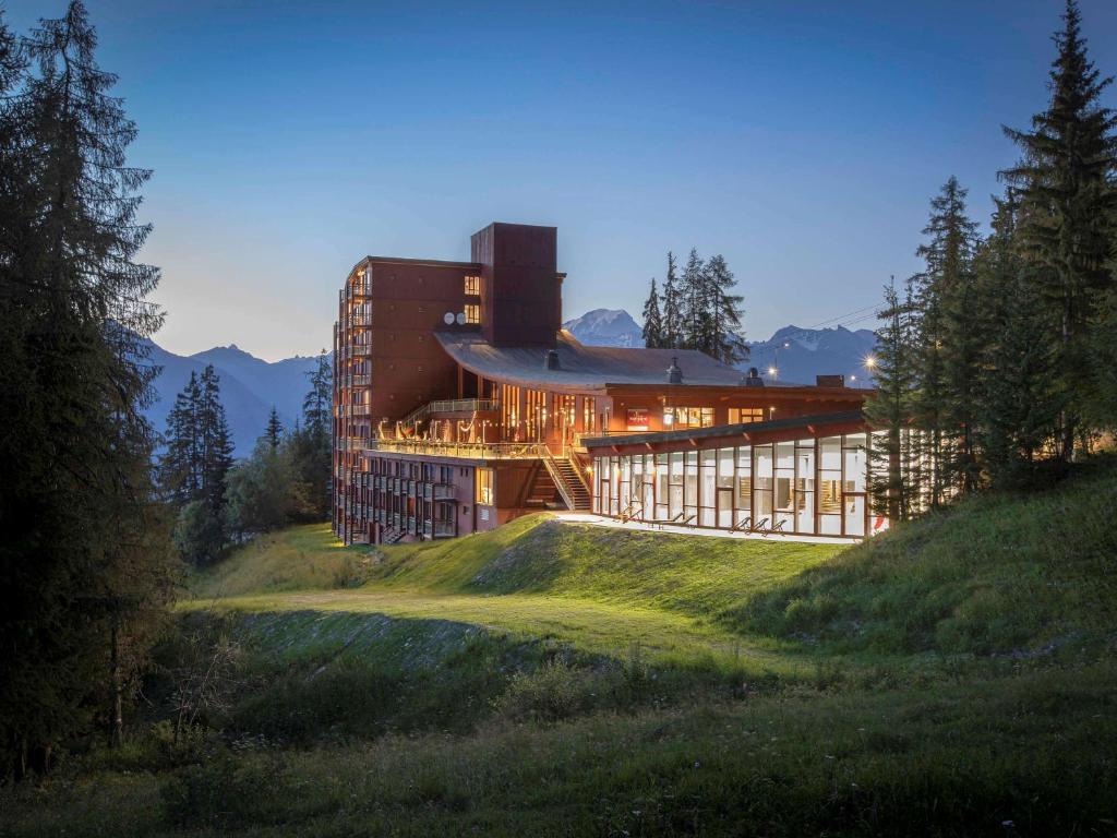 un bâtiment au sommet d'une colline herbeuse dans l'établissement Altezza - Arc 1800 Hotel & Spa - ex Mercure, à Arc 1800