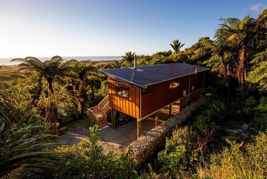 a cabin in the middle of a forest with palm trees at Treescapes in Punakaiki