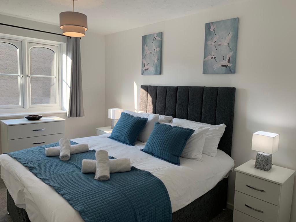 a bedroom with a large bed with blue pillows at Watford Gemini - Eton 1 - Nr Watford Junction, M1 ,M25 in Watford