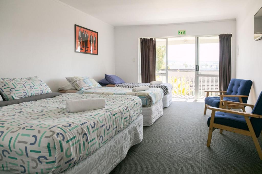 a hotel room with two beds and a chair at Finlay Jack's Backpackers in Taupo