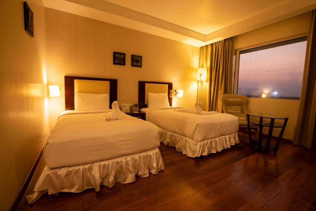 pokój hotelowy z 2 łóżkami i oknem w obiekcie Grand Gardenia w mieście Tiruchchirāppalli