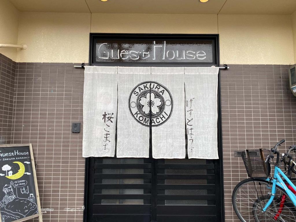 a guest house sign above a door with a guest house banner at Sakura Komachi in Kyoto