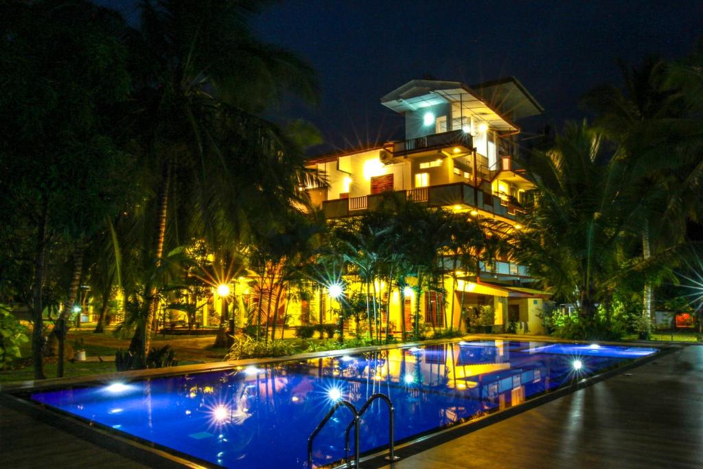 un hotel con una gran piscina por la noche en Hotel Nilketha Yala Tissamaharama, en Tissamaharama