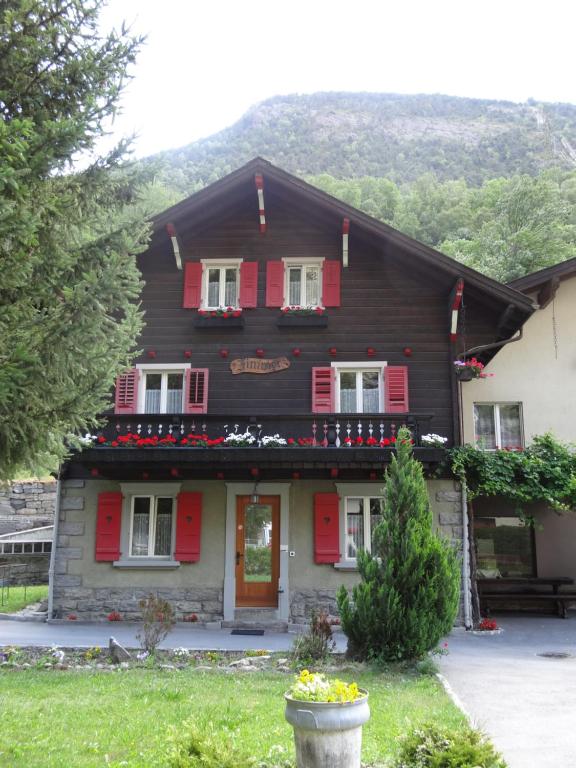 a wooden house with red shutters and a porch at Zimmervermietung Ackersand in Stalden