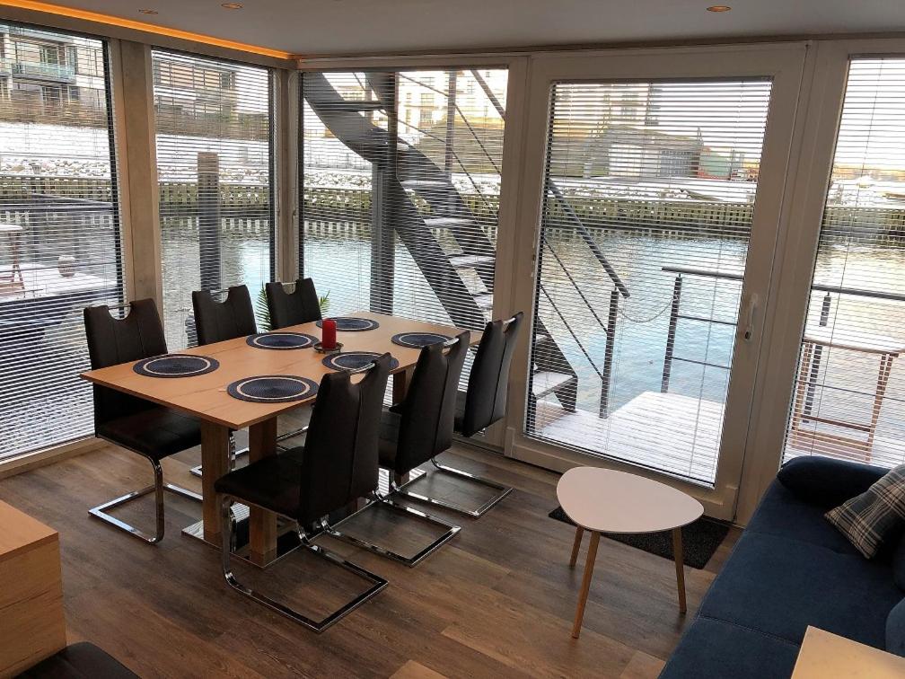 a dining room with a table and chairs and windows at MarinaVilla in Nykøbing Falster