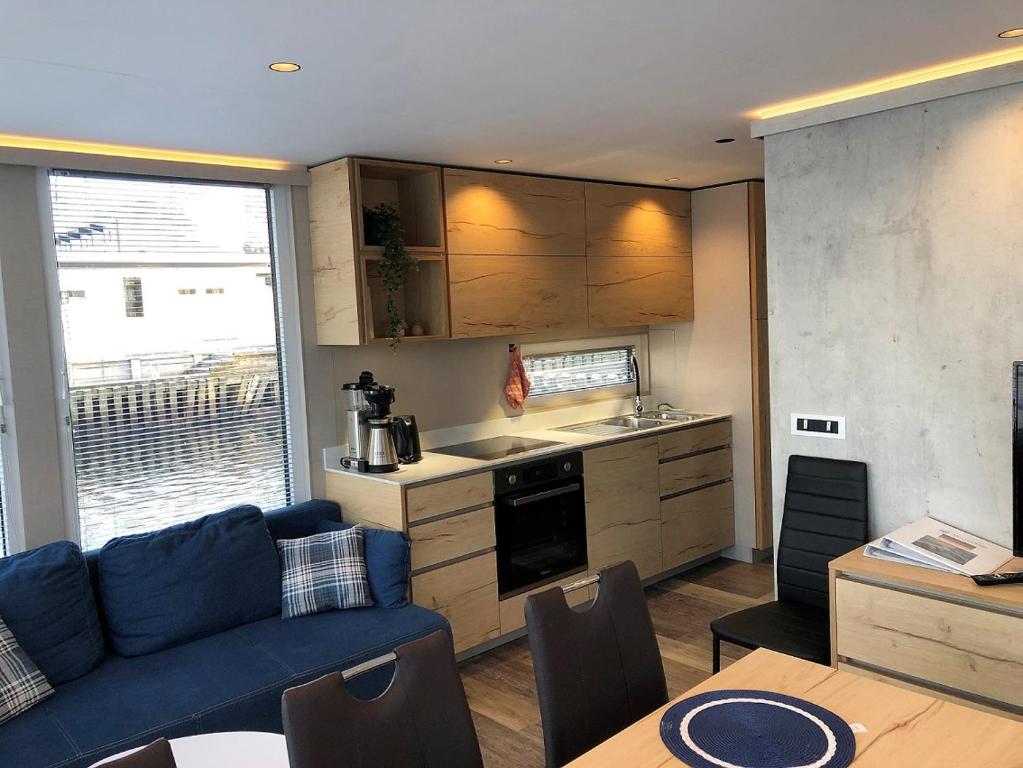 a living room with a blue couch and a kitchen at MarinaVilla in Nykøbing Falster