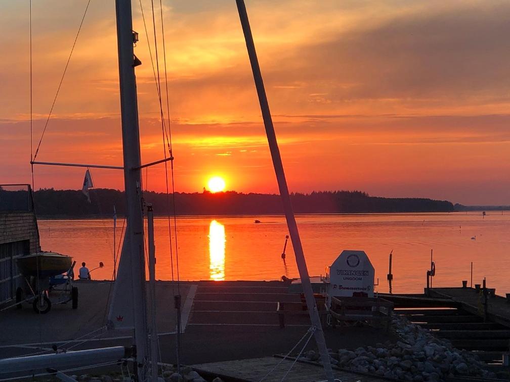 a sunset over a body of water with a boat at MarinaVilla in Nykøbing Falster