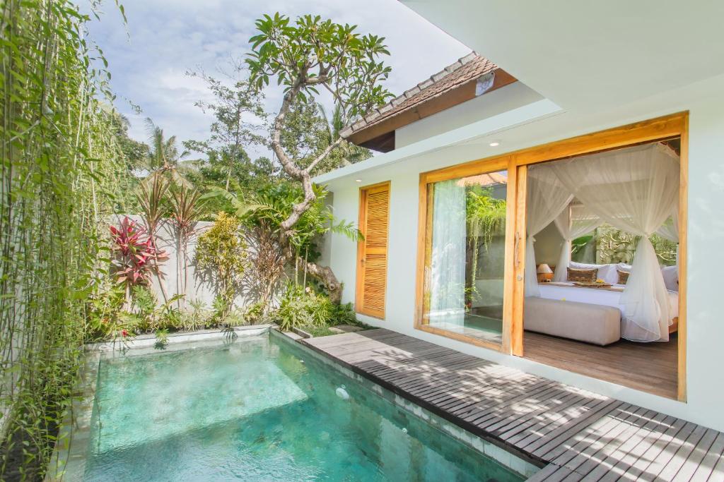 a villa with a swimming pool and a bedroom at Reswaha Villas by Pramana Villas in Ubud