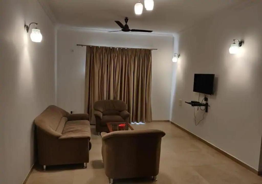 a living room with two chairs and a tv at Areia De Goa - Sunrise By Leela Homes in Arpora