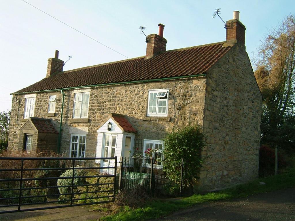 an old stone house with a gate in front of it at Cottage with amazing views of the North York Moors in York