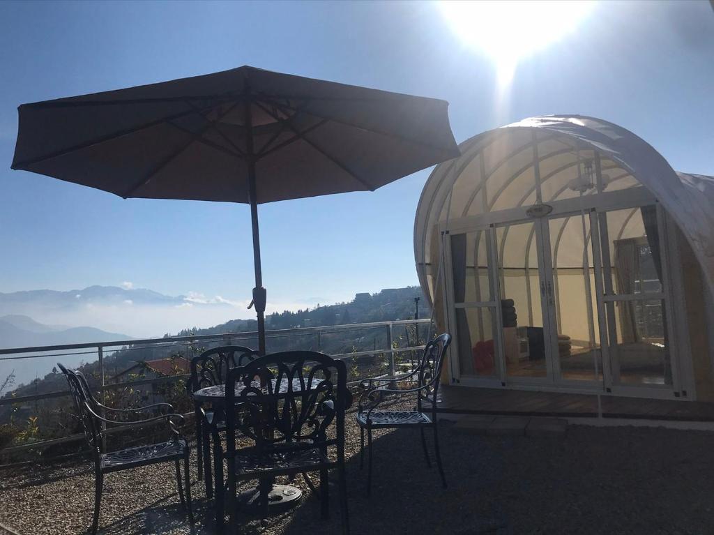 einen Tisch und Stühle mit Sonnenschirm auf dem Balkon in der Unterkunft 清境花鳥蟲鳴高山露營區 in Jen-chuang