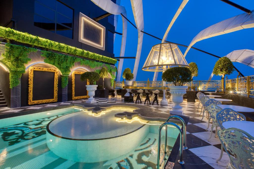 A rooftop pool terrace with ornate seating, topiary and a small circular spa.