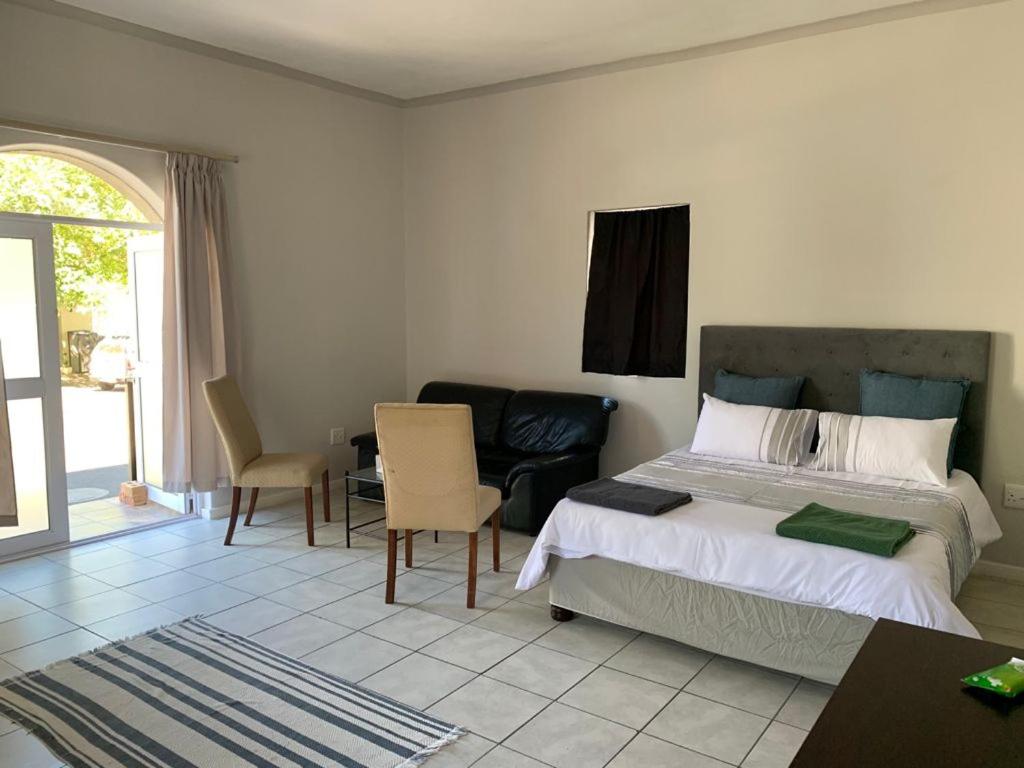 a bedroom with a bed and a table and chairs at Bright open-plan apartment close to wine tram in Franschhoek