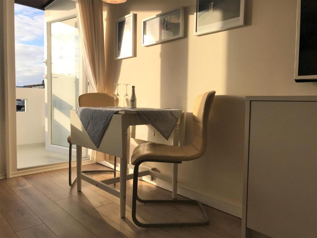 una sala da pranzo con tavolo, sedie e una finestra di Ferienwohnung Strandmarie, Haus Loreley, App. 14 a Sankt Peter-Ording