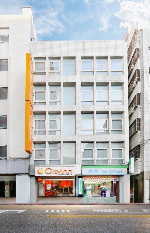 a large white building with a store on a street at Cityinn Hotel Taipei Station Branch I in Taipei