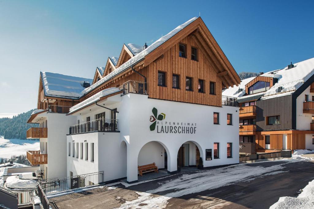 ein großes weißes Gebäude mit einem Holzdach in der Unterkunft Alpenheimat Laurschhof in Fiss