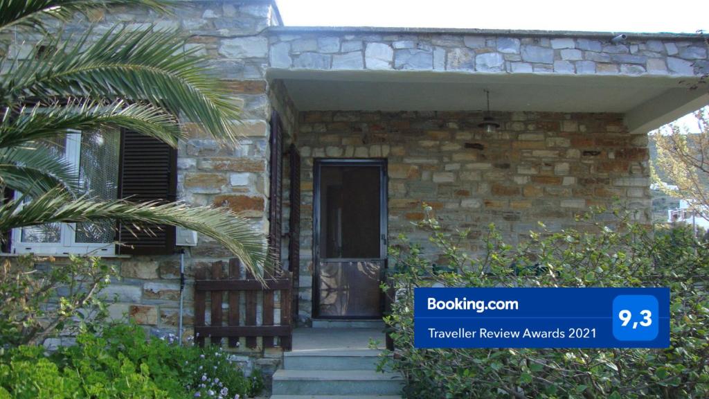 a stone house with a door and a palm tree at Little Stone House near the Beach in Agios Ioannis Tinos