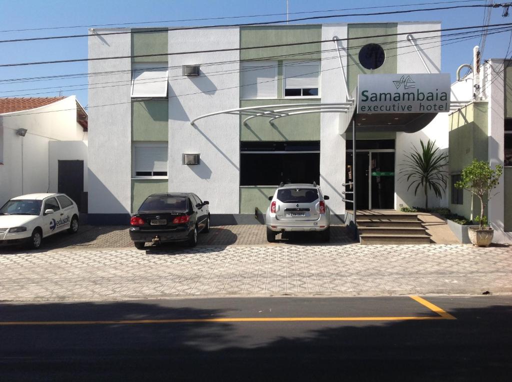 tres autos estacionados en un estacionamiento frente a un edificio en Samambaia Executive Hotel, en Taubaté