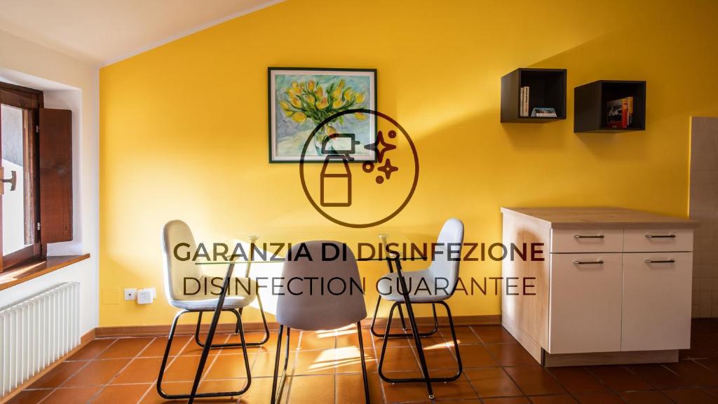 a kitchen with a yellow wall with a sink and chairs at Italianway - Castellana 68 in Udine