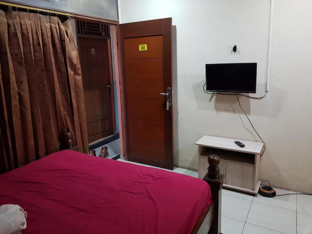 een slaapkamer met een rood bed en een televisie bij Hotel Alifah 1 Syariah in Rawabokor Dua