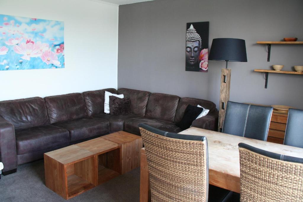 een woonkamer met een leren bank en een houten tafel bij Schorrebloem 1 in Nieuwvliet