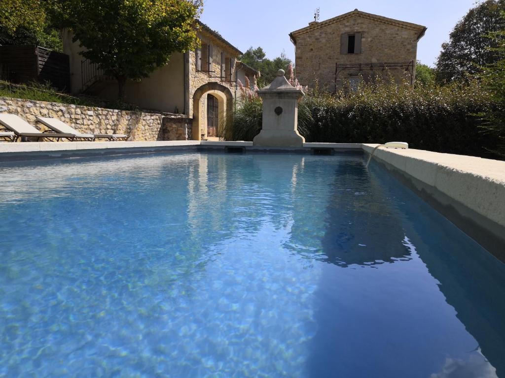 uma piscina com água azul em frente a uma casa em Mas en Baronnies Provençales em Eygaliers