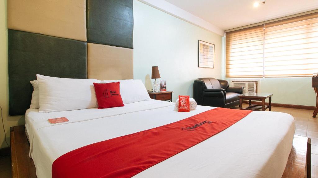 - une chambre avec un grand lit et une couverture rouge dans l'établissement RedDoorz at Timog Avenue Quezon City, à Manille