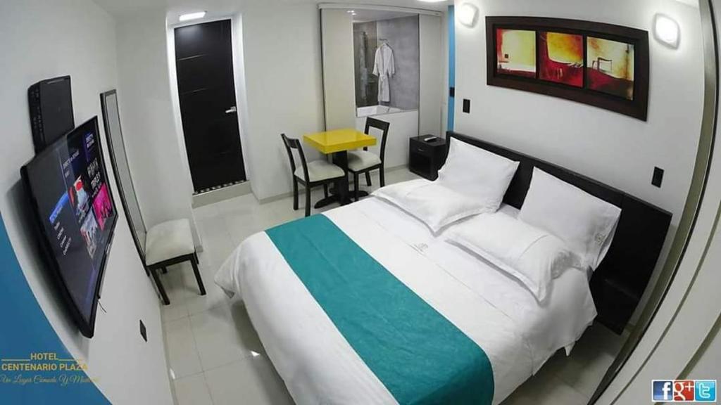 Un dormitorio con una cama grande y una mesa pequeña. en Hotel Centenario Plaza, en Belén
