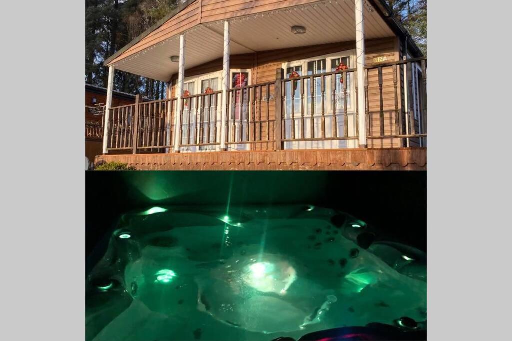 a house with a hot tub in front of it at Cosy Woodlands Lodge with Hot Tub, Decking & Garden in Beattock