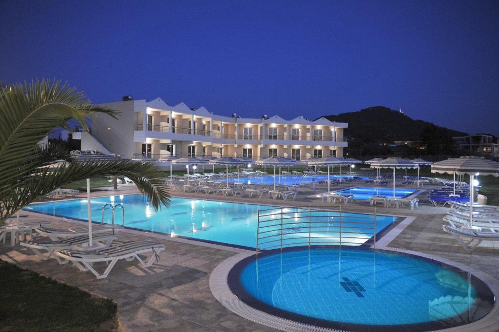 a large hotel with a large swimming pool at night at Emerald Hotel in Kremasti