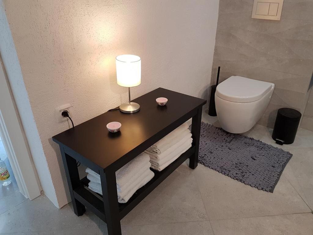 bagno con tavolo, lampada e servizi igienici di Apartment Aduro a Šibenik