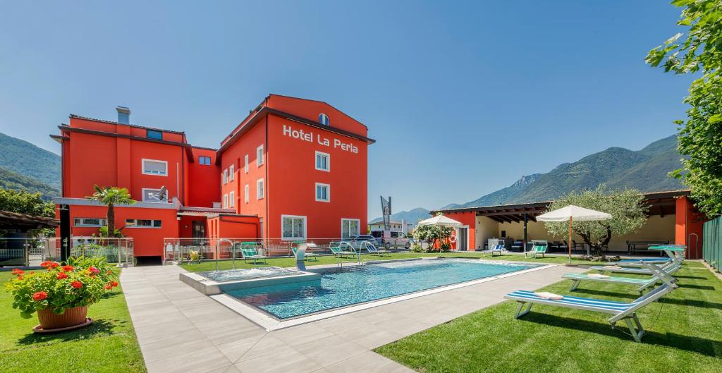 a hotel with a swimming pool in front of a building at Hotel La Perla in SantʼAntonino