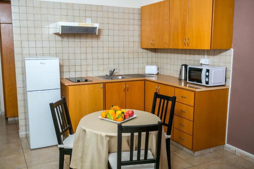 a kitchen with a table with a plate of fruit on it at Crystallo Apartments in Paphos