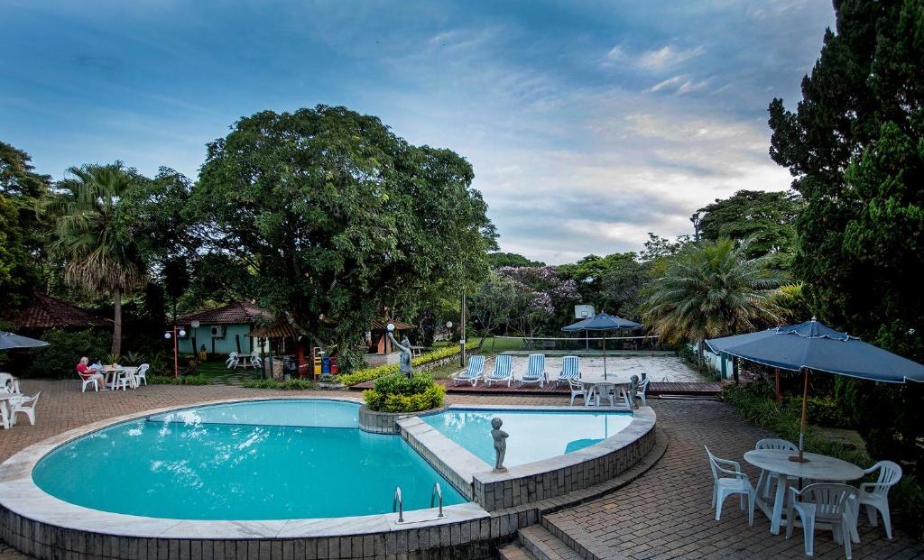 a pool at a resort with tables and chairs at Villa Buonabitacolo in São João del Rei