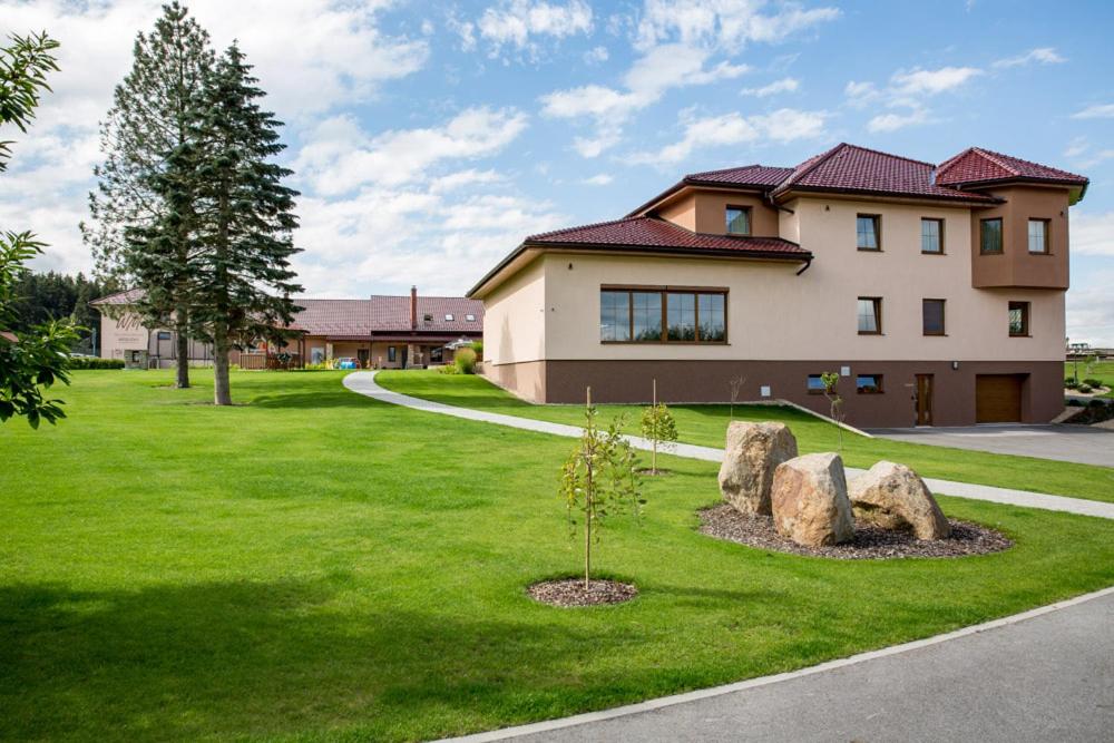 une maison avec des rochers et un arbre dans l'herbe dans l'établissement Wellness penzion Medličky, à Batelov