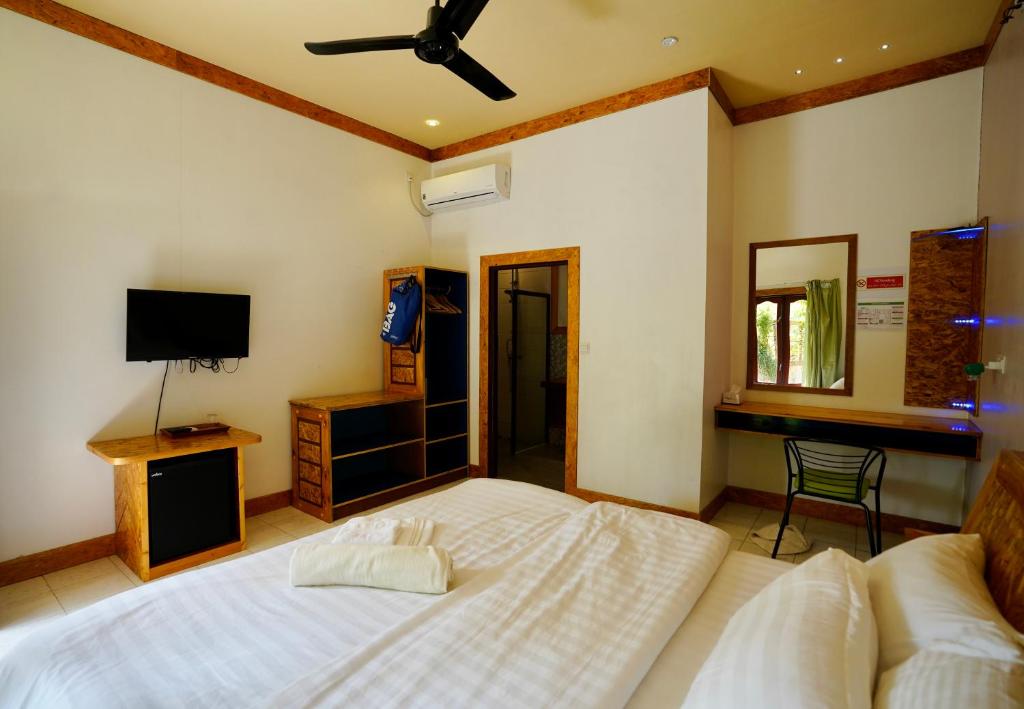 a bedroom with a bed and a desk and a television at Veli Beach Inn in Mathiveri