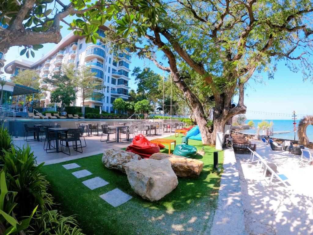 a park with rocks and a tree and a building at Sonrisa Srirachaที่พักติดทะเล in Si Racha